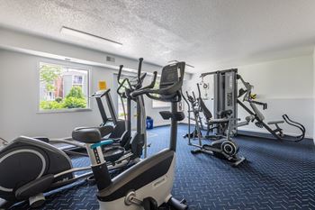 A gym with a row of treadmills and elliptical machines. at Windsor Crest Apartments, Davenport , IA